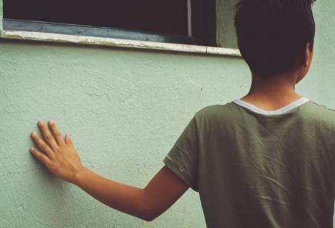 A boy stands alone in Schisto refugee camp, Greece